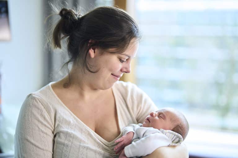Mother in neonatology holding baby in her arms and looking happily into his eyes