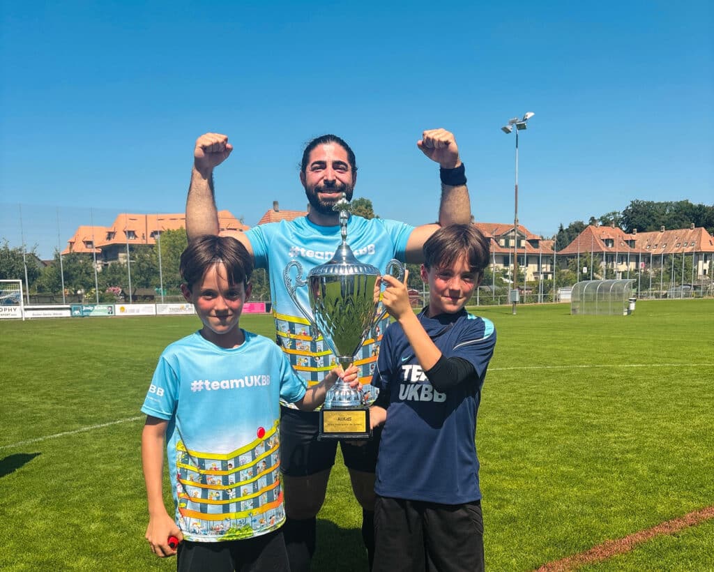 Two boys hold aloft the winner’s trophy from the 2026 AllKidS Football Tournament